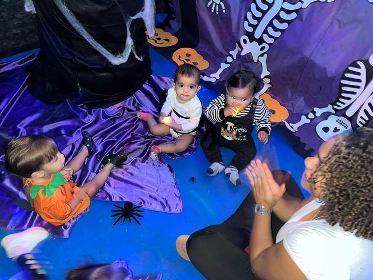 Bebês do Berçário da Creche Escola Santa Beatriz em atividade sensorial na decoração de Halloween, acompanhados pela professora